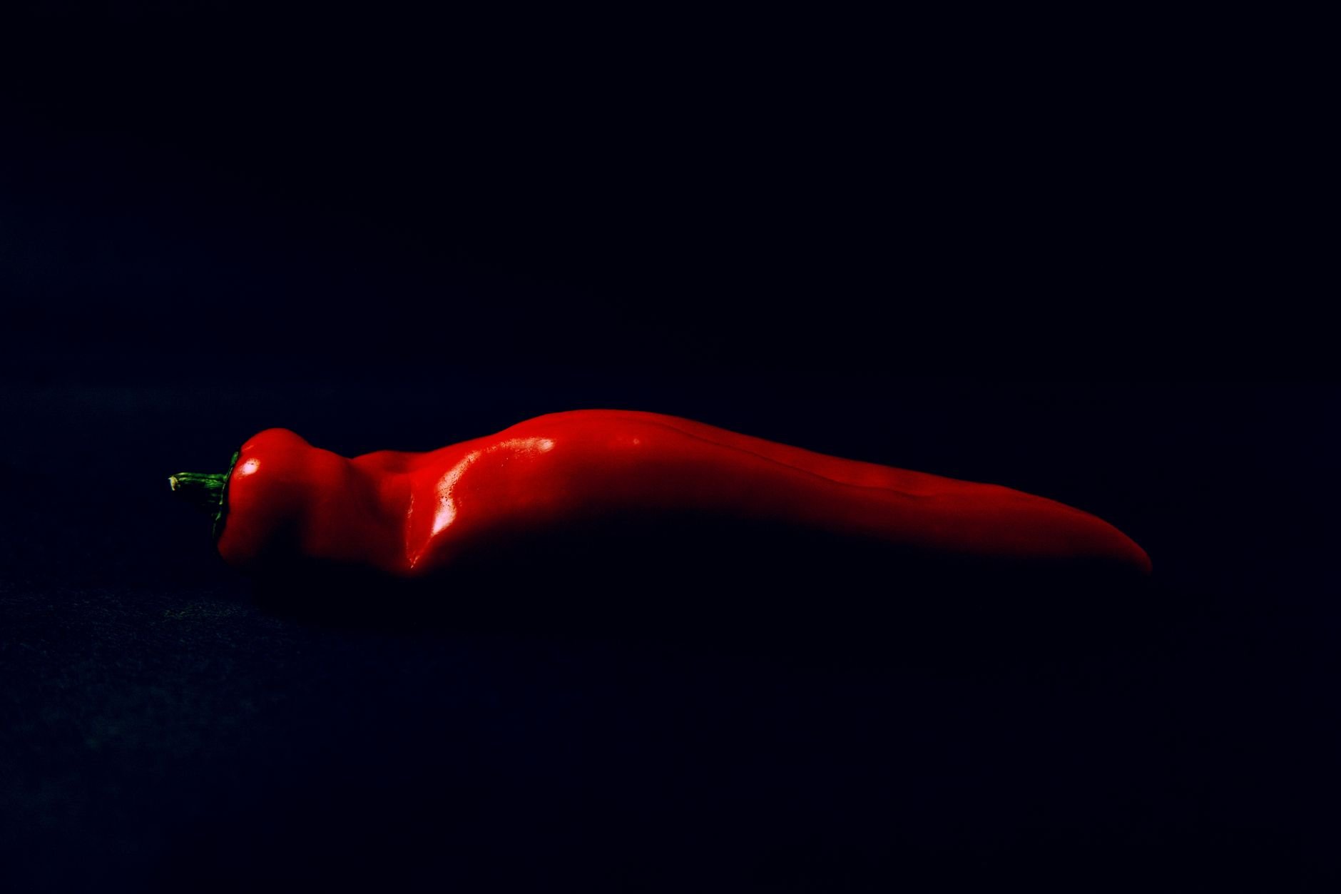 Vibrant red chili pepper on a dark background, the kind of ingredient we start with